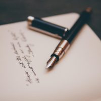作者坐在书桌前对着摊开的稿纸修改分类清单，手边放着一支笔和一杯凉掉的茶